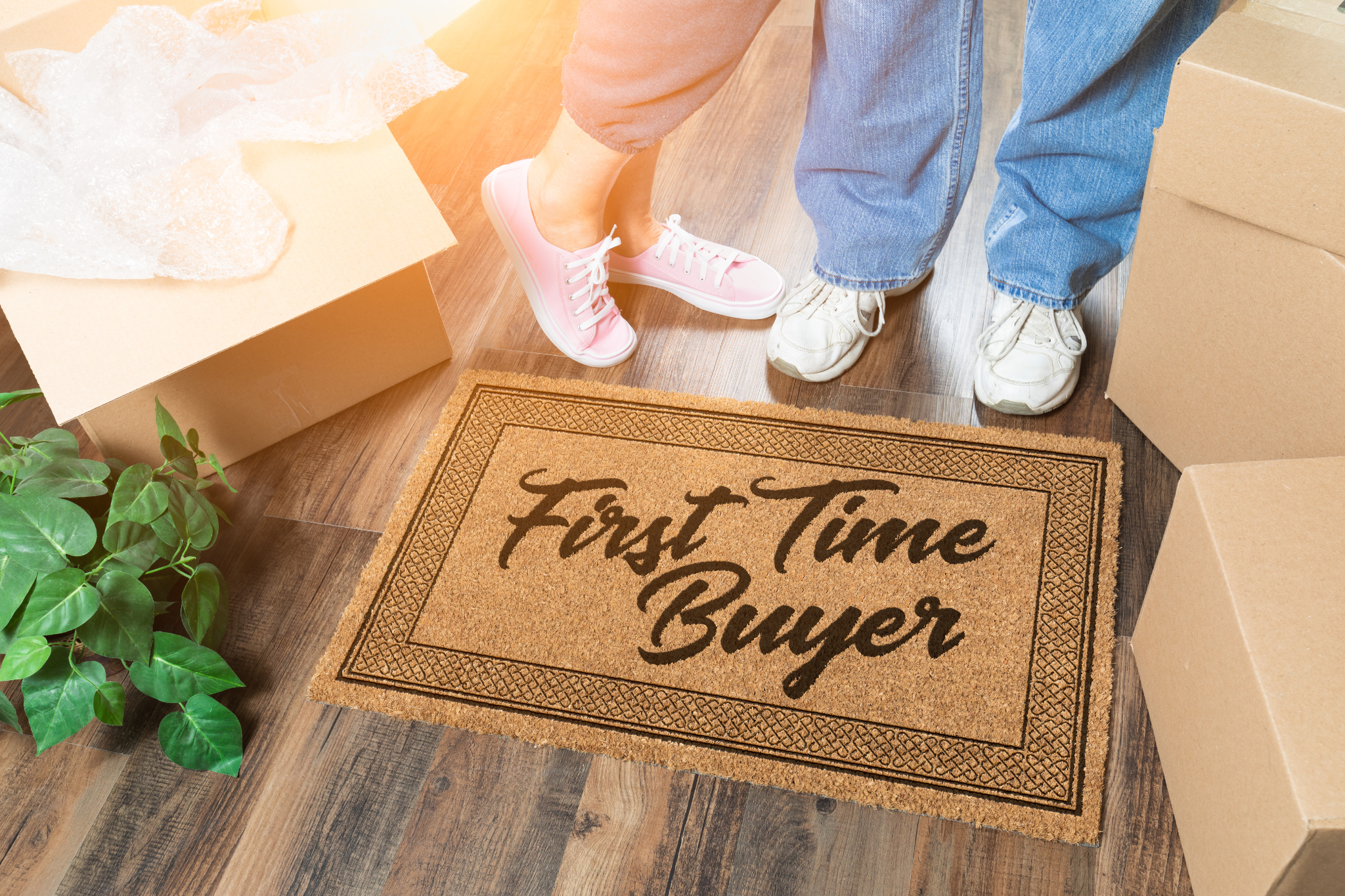First-time homebuyers standing by moving boxes and a welcome mat in a new home at Honaker Farms in Johnston County, NC